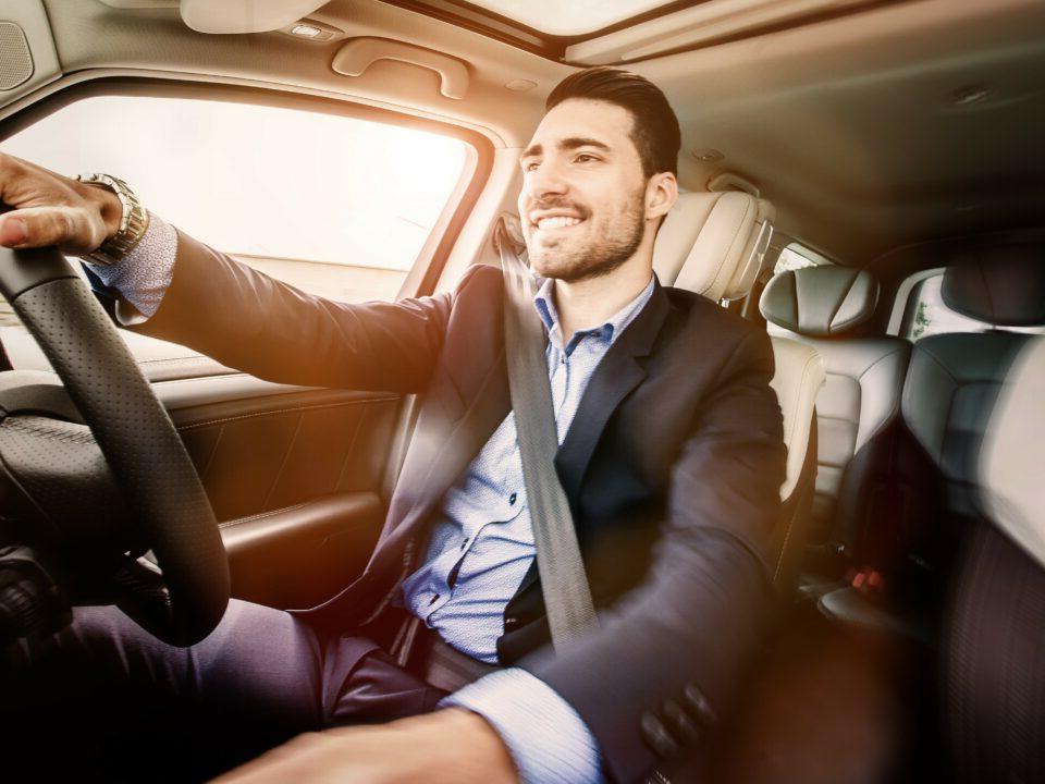 man in a suit driving a car